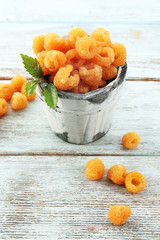 Yellow raspberries in cup on wooden background