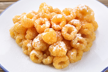 Yellow raspberries in white plate on wooden table, closeup