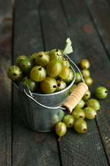 Green gooseberry in pail on wooden background