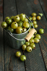 Green gooseberry in pail on wooden background