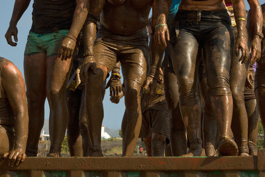 Group of people jumping over an obstacle during the Inferno run mud race
