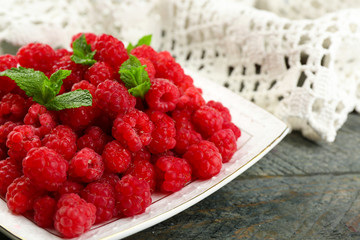 Sweet raspberries on plate on wooden  background