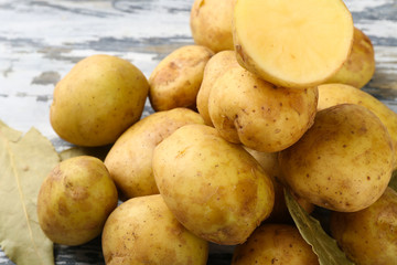 young potatoes with bay leaves on wooden table close up