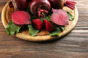 Young beets with leaves on wooden table close up