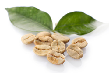 Heap of green coffee beans with leaves isolated on white