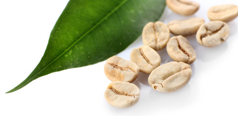 Heap of green coffee beans with leaf isolated on white