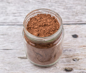 Obraz na płótnie Canvas Brown pure cocoa powder in a mason jar over rustic wooden background