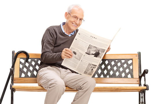 Senior reading a newspaper seated on a bench