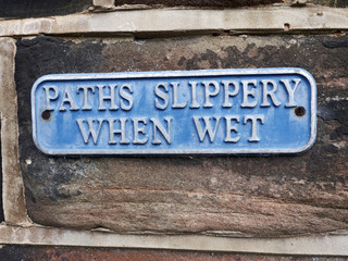 Paths slippery when wet sign on outside wall UK