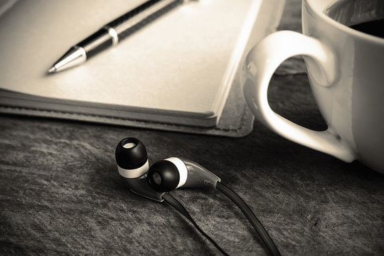 close up of earphone with coffee and notebook on old wooden tabl