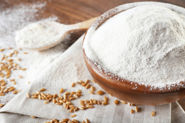 Fototapeta na wymiar Whole flour with wheat on wooden table, closeup