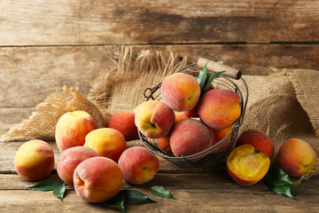 Ripe peaches in basket on wooden background