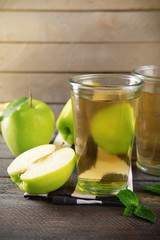 Glasses of apple juice on wooden background