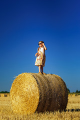 Naklejka na ściany i meble Cute little girl with sunglasses posing on the haystack