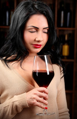 Pretty young woman with wineglass on wine shelf background