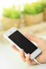 Music smartphone in female hand, on light background