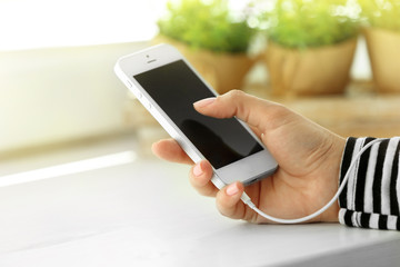 Music smartphone in female hand, on light background