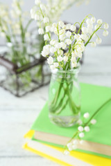 Lily of the Valley in bottles on white wooden background