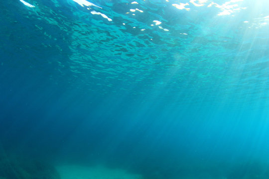 Underwater blue background in ocean with sunlight