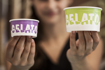 Una gelataia mostra due coppette gelato colorate