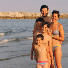 family of fieve person on the beach in summer