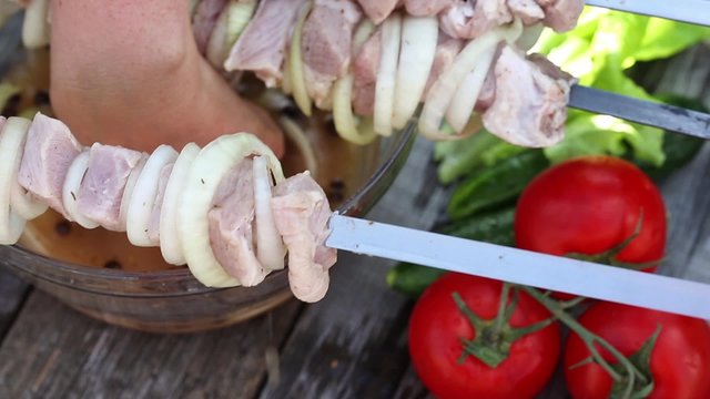 Woman sticking meat on skewers, cooking process
