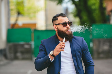 man with a beard smokes electronic cigarette