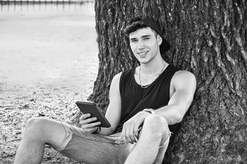 Young Man with Tablet or Ebook Reader Relaxing at Park