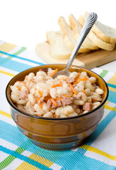 Navy Bean Soup – A bowl of navy bean soup. On a plaid background with bread.