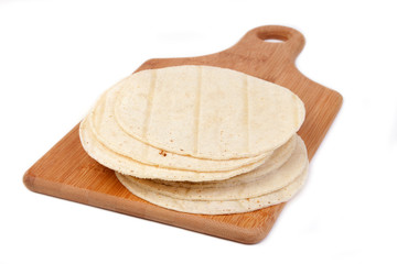 Corn Tortilla Stack – A stack of corn tortillas on a wooden cutting board. Isolated on a white background.