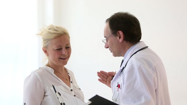 Reassuring doctor holding a clipboard giving good news to a blonde female patient