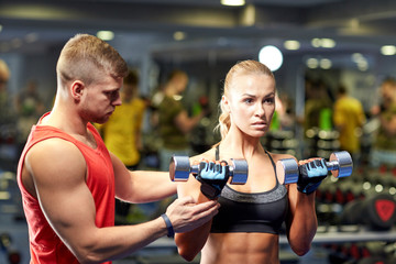 Fototapeta na wymiar young couple with dumbbells flexing muscles in gym