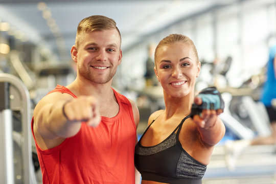 happy man and woman pointing finger to you in gym