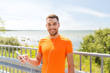 smiling young man with smartphone and earphones