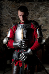 Knight Standing With Head Bowed in Prayer and Metal Sword 