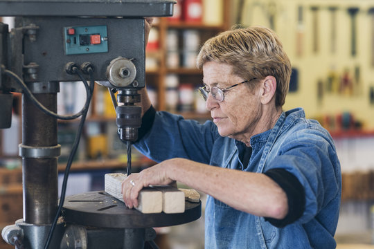 Woman artist using a drilling machine in workshop.