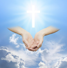 Worshiping the Divine Source of Love and Light - female hands cupped with a shining white cross...