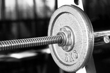 Barbell focused on 5 kg plate black and white