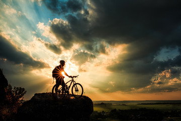 Silhouette of a biker and bicycle on sky background.