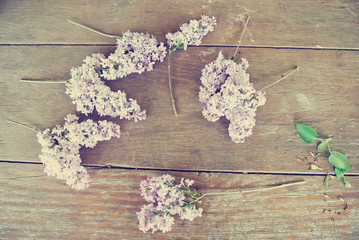 Lilac flowers lying on the rustic wooden table; shot from above. Photo filtered in faded, washed out, retro, Instagram style. Romantic, nostalgic vintage concept.