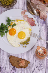 Fried eggs with fresh parsley and a green peas and smoked meat