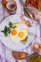 Beer and fried eggs with fresh parsley, a green peas and smoked