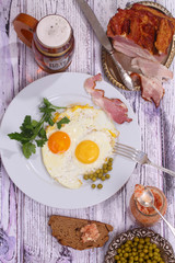 Beer and fried eggs with fresh parsley, a green peas and smoked