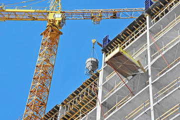 Crane lifting concrete mixer container against blue sky