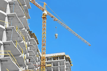 Crane lifting concrete mixer container against blue sky