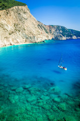 Porto Katsiki beach in Lefkada island, Greece. Beautiful view over the beach. The water is turquoise and there are tourists on the beach and a boat on the sea.