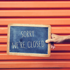 man hand with a chalkboard with the text sorry we are closed