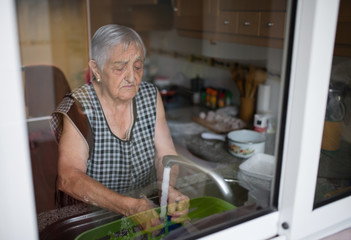 Elderly woman washing dishes