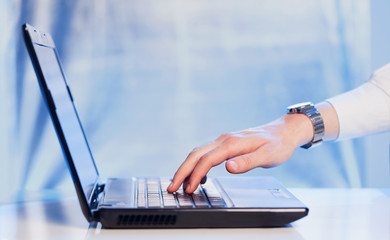 Businessman pressing modern laptop computer on colorful backgrou