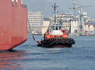 A tugboat pushes the cargo ship outside the port area.